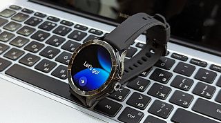 Круглые часы Xiaomi на клавиатуре ноутбука, на экране приветствие при настройке