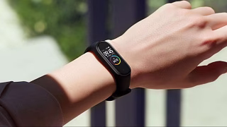 Чёрный фитнес-браслет Xiaomi на руке девушки: 09:45 и 6410 шагов на экране