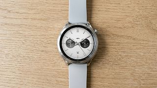 Смарт-часы Xiaomi Watch S4 с круглым AMOLED-экраном на деревянном столе, на дисплее время и кольца активности