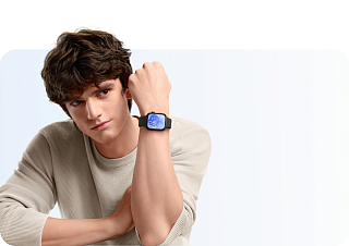 Молодой человек в бежевом свитере с прямоугольными Huawei Watch Fit 3 на запястье, синий циферблат