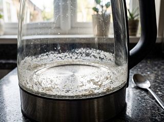 Белый налёт накипи на дне и нижней стенке стеклянного чайника виден насквозь через стекло
