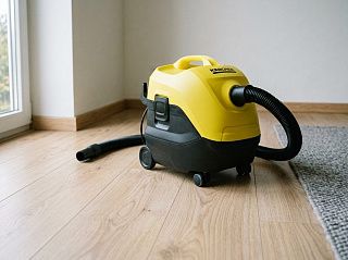 Пылесос с аквафильтром Karcher DS 6 на светлом ламинате у края серого ковра, шланг подключён к корпусу
