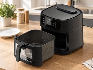 Аэрогриль Жароваров на светлой кухонной столешнице, рядом белая тарелка для масштаба
